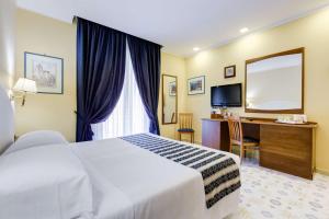 a hotel room with a bed and a desk and a mirror at Best Western Hotel La Solara in Sorrento