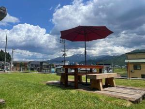einen Picknicktisch mit einem roten Regenschirm auf dem Feld in der Unterkunft Jonobien - Vacation STAY 13238 in Minami Uonuma