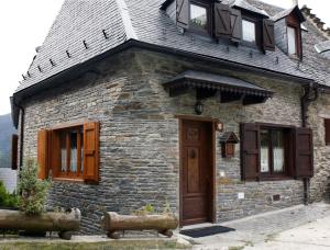 a stone house with a wooden door and windows at Apartamentos Valle de Aran in Mont