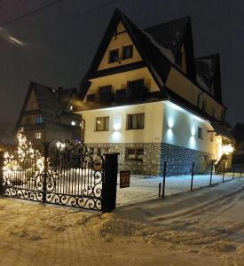 ein Haus mit einem Zaun davor in der Nacht in der Unterkunft Willa CHWOST zlokalizowana w pobliżu Term i Zakopanego in Zakopane