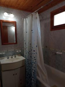 a bathroom with a shower curtain and a sink at Cabaña Ruca Kushe in Lago Puelo