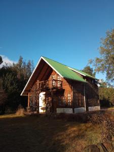 een grote houten hut met een groen dak bij Cabaña Ruca Kushe in Lago Puelo