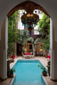 a pool in a courtyard with an archway and a house at Riad Lyla in Marrakesh