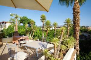 un patio con mesa, sillas y palmeras en Riad Lyla, en Marrakech