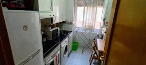 uma pequena cozinha com um frigorífico e uma janela em Habitación CDV em Madri