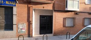 ceglany budynek z czarnymi drzwiami w obiekcie Habitación CDV w Madrycie