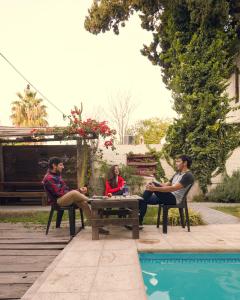 a group of people sitting around a table by a pool at Chill Inn Hostel in Mendoza