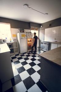 un hombre parado en una cocina mirando en un refrigerador en Chill Inn Hostel en Mendoza