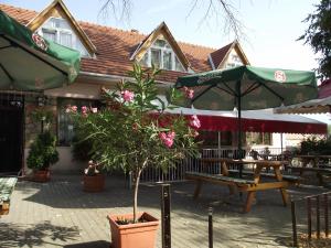 a patio with a table and a bench and umbrellas at Ludas Fogadó in Nagyalásony