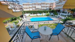 a balcony with a table and chairs and a swimming pool at Blue Deluxe Apartment in Kallithea Halkidikis