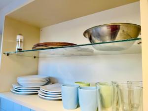 a shelf with plates and cups on a counter at Luminoso departamento con vista! in Cordoba