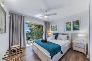 a white bedroom with a bed and a balcony at Sea Views on Shingley in Airlie Beach