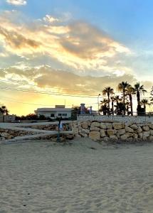 un tramonto sulla spiaggia con un muro di pietra di Il mare di Ciccio ad Avola