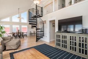 a living room with a staircase and a large television at A Sea View Cottage by Oak Island Accommodations in Oak Island