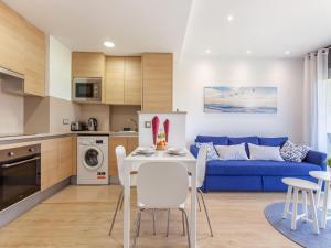 cocina y sala de estar con sofá azul en Belvilla by OYO Modern Apartment in Palamos, en Palamós