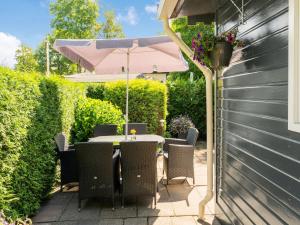 una mesa y sillas con una sombrilla en el patio en Lovely Wooden Chalet with garden in Reutum en Reutum