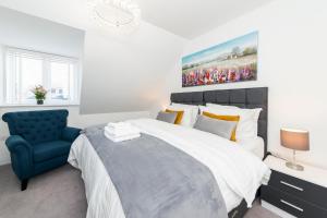 a bedroom with a large bed and a blue chair at Greenfield Holiday Homes in Bracknell