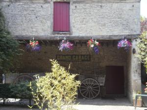 ヴァローニュにあるLogis Le Grand Hôtel du Louvreの赤い窓と花が咲くレンガ造りの建物