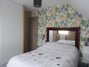 a bedroom with a bed with a tropical wallpaper at Holiday home, Frehel in Frehel