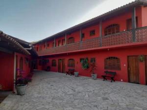 a red building with benches in a courtyard at Pousada Blues in Ipiabas