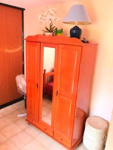 a wooden cabinet with a mirror and a lamp on top at Escale au jardin des plantes in Fort-de-France