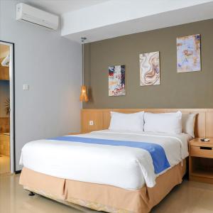 a bedroom with a large white bed in a room at Golden Tulip Balikpapan Hotel & Suites in Balikpapan