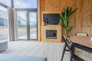 a living room with a table and a tv and a fireplace at Lodge Ojos de Nieve in Malalcahuello