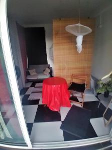 a living room with a red table and a couch at Chambre avec cuisine et SDB semi-privatives separées dans un ecrin de verdure in Les Abymes