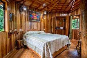 1 dormitorio con 1 cama en una habitación de madera en Casitas del Bosque Monteverde., en Monteverde
