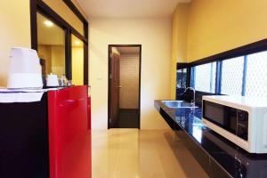 a kitchen with a microwave and a red refrigerator at The Middle Town SHA in Chiang Rai