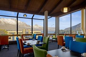 a restaurant with tables and chairs with mountains in the background at Copthorne Hotel & Apartments Queenstown Lakeview in Queenstown