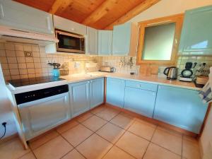 cocina con armarios blancos, fregadero y microondas en Appartement Samoëns, 2 pièces, 4 personnes - FR-1-624-112 en Samoëns