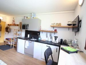 a kitchen with white cabinets and a black counter top at Studio Chamrousse, 1 pièce, 3 personnes - FR-1-549-95 in Chamrousse