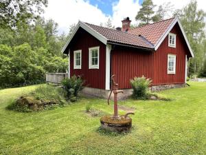 une petite maison rouge avec une statue devant elle dans l'établissement Holiday home ULRIKA II, à Rimforsa
