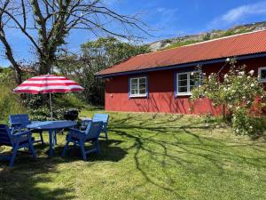 una mesa y sillas con sombrilla frente a una casa roja en Holiday home Skärhamn VII, en Skärhamn