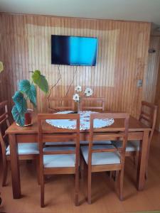 a dining room table with chairs and a tv on a wall at a 7km de Puerto Varas, Nueva Braunau hasta 6 personas in Santa María Línea
