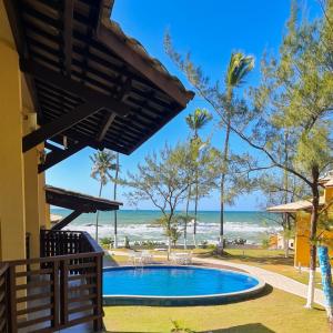 uma piscina com a praia ao fundo em Paraíso PÉ NA AREIA no coração do Litoral Norte - FRENTE MAR - Loft projetado para que você tenha a melhor experiência em hospedagem - condomínio mais procurado da Estrada do Côco - Varanda com vista espetacular para o mar - lazer e TRANQUILIDADE em Camaçari