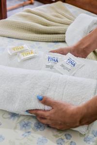 a person holding a pile of towels on a bed at Pousada da Tina in Ubatuba