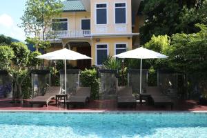 Ban Khlong Lat Bua KhaoBaan Chao Khun Hotel的房子前面有椅子和遮阳伞的游泳池