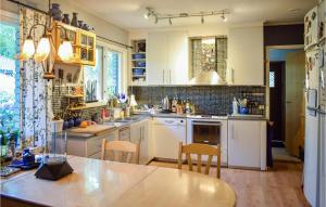 a kitchen with white cabinets and a table and chairs at Stunning Home In Ljungbyholm With Sauna in Ljungbyholm
