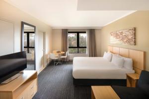 a hotel room with a bed and a flat screen tv at Mercure Sydney Macquarie Park in Sydney
