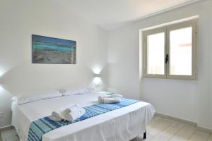 a white bedroom with a bed with towels on it at Biriola EcoResort Cala Gonone in Cala Gonone