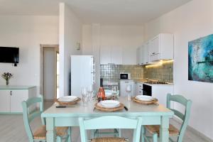 a dining room with a table and chairs and a kitchen at Biriola EcoResort Cala Gonone in Cala Gonone