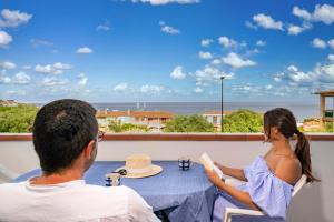 a man and a woman sitting at a table looking out at the ocean at Biriola EcoResort Cala Gonone in Cala Gonone