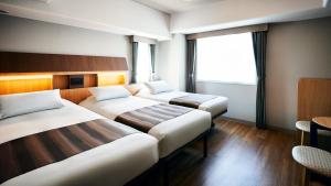 東京にあるホテル モンテ エルマーナ東京のベッド2台と窓が備わるホテルルームです。