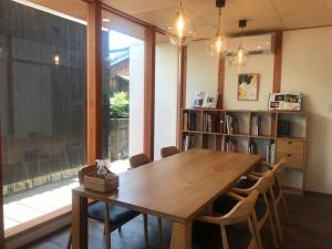 Quaint House Naoshima في ناووشيما: غرفة طعام مع طاولة خشبية ورف كتاب