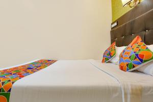 a bedroom with a white bed with colorful pillows at Hotel Aksa in Mumbai