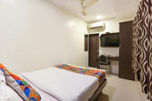 a bedroom with a bed and a desk and a tv at Hotel Aksa in Mumbai