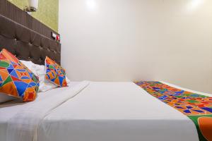 a white bed with colorful pillows on top of it at Hotel Aksa in Mumbai