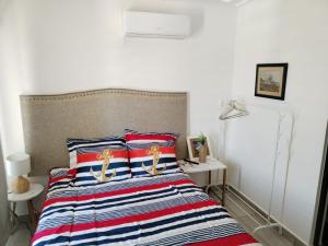 1 dormitorio con 1 cama con colcha a rayas en Hermoso Departamento nuevo con acceso a Alberca, en Mazatlán